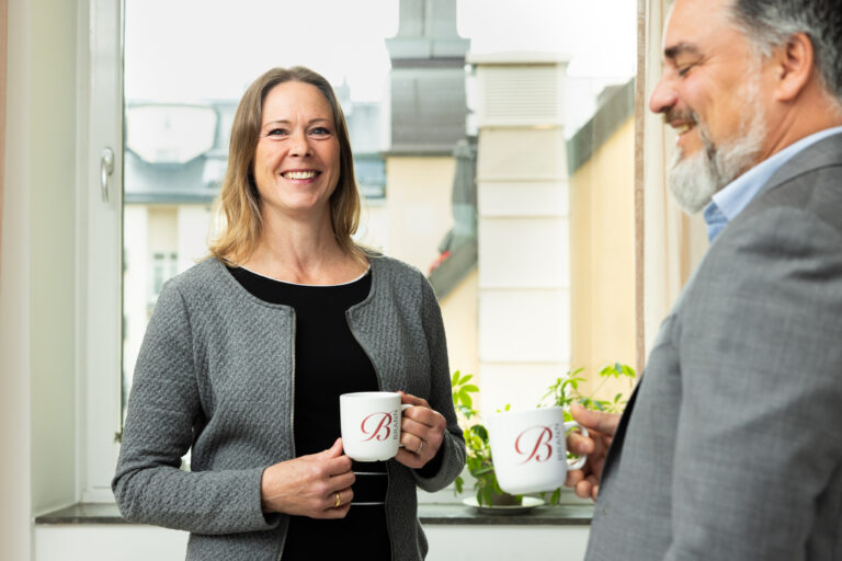 Medarbetare som står och pratar med kaffekopp i händerna.